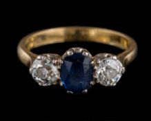 An 18ct gold, sapphire and diamond three-stone ring: the oval sapphire approximately 7mm long x 5.