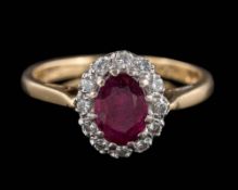 An 18ct gold, ruby and diamond oval cluster ring: the oval ruby within a surround of round,