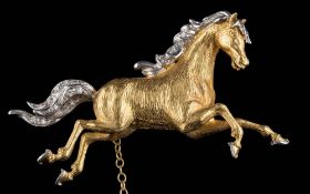 An 18ct gold and diamond-set two tone 'galloping horse' brooch: mane and tail set with single-cut