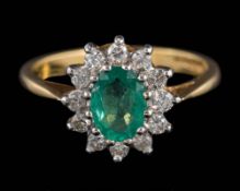 An 18ct gold, emerald and diamond oval cluster ring: the oval emerald within a surround of round,