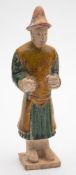 A Chinese sancai-glazed pottery figure of a groom: his robes decorated in green and ocre,
