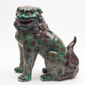A large Japanese Kutani model of a Shishi: seated on it's haunches, decorated in green, aubergine,
