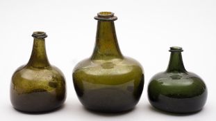 A group of three early 18th Century glass wine bottles: one of onion shape, two of mallett form,