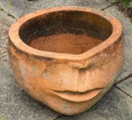 A large terracotta jardiniere: with abstract decoration in the form of the lower half of a human