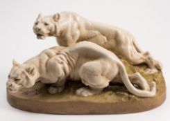 A large Royal Dux group of two crouching lionesses: on naturalistic green mound base,