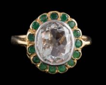 A diamond and emerald oval cluster ring: with central cushion-shaped diamond approximately 10mm