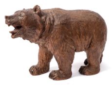 An early 20th century carved linden wood Black Forest bear: raised on all fours with glass inset