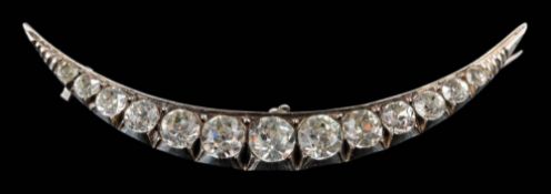 A paste set crescent brooch: with thirteen graduated white pastes, approximately 68mm long.
