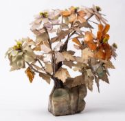 An Oriental carved hardstone flower arrangement: mounted in a polished hardstone naturalistic base,