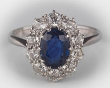 A sapphire and diamond oval cluster ring: the central oval sapphire approximately 8.2mm long x 5.