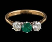 An 18ct gold, emerald and diamond three-stone ring: the circular emerald between round,