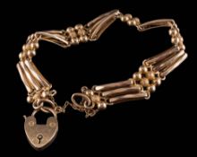 An Edwardian three bar gate-link bracelet: stamped '15', with attached heart-shaped padlock clasp,