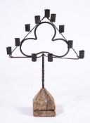 A 19th Century French wrought iron triangular candle holder:, on a limewood base,