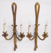 A pair of gilt metal twin-branch wall lights: with ribbon tied backplate and a pair of spiral twist