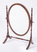 A mahogany oval swing frame toilet mirror:, with ring turned uprights and dual splayed end supports.