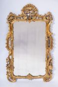 A 19th Century carved giltwood mirror:, of cartouche-shaped outline,