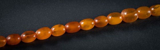 An amber bead single-string necklace: with twenty nine graduated oblong beads,