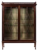 An Edwardian mahogany display cabinet:, with a pierced fret geometric surmount and turned finials,
