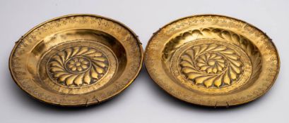 A near matching pair of 18th century brass alms dishes: with central flowerhead embossed decoration,