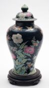 A Chinese famille noire baluster vase and cover with hardwood stand: painted with birds, prunus,