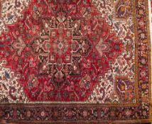 A Heriz carpet:, the red field with a central indigo and red geometric flowerhead pole medallion,