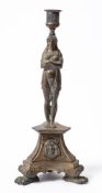 A late 19th century bonze figural candlestick: the urn-shaped nozzle supported by an Egyptianesque