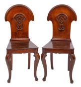 A pair of Victorian oak hall chairs:, the solid domed arch moulded backs with carved foliate,