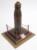A WWI trench art shell memorial: the 5lb shell mounted vertically on a square stepped plinth with