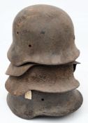 A group of four WWII German battlefield relic M40 pattern steel helmets: (4)