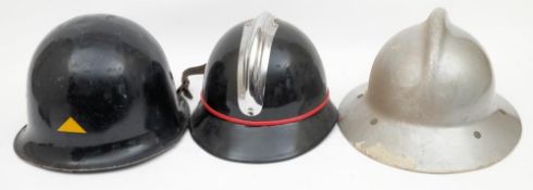 Three mid 20th century French Fire Service helmets: comprising a black steel helmet with gilt