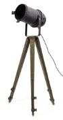 An overpainted spotlight mounted on a military style tripod,
