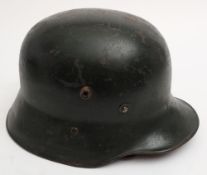 A WWI German M16 pattern steel helmet: overpainted dark green with brown leather liner,