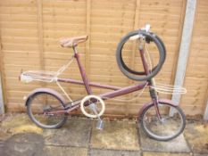 A mid 20th century Moulton Standard bicycle: red frame with chrome plated handlebars,