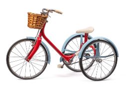 A child's tricycle, probably by Raleigh: the red frame with light blue mud guards,