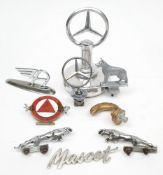 A collection of various car mascots: including a Mercedes-Benz Star and a larger desk top version,