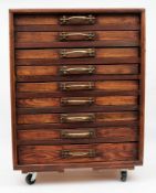 A scratch built stained pine collector's cabinet of nine drawers with brass handles on castors,