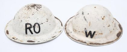 Two WWII Warden's Brodie pattern steel helmets: both in white one marked 'W' the other 'RO',