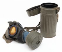 A WWII period German GM30 gas mask: black rubber mask with blue metal mounted glass lenses and
