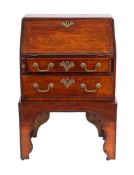 A George III mahogany bureau:, of small size, on a later integral stand,