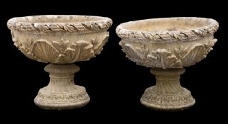 A pair of reconstituted stone circular garden pedestal urns:, decorated with shells and foliage,