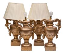 A harlequin set of four carved giltwood lamps: in the form of neo-classical urns on square bases,