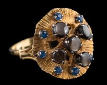 A sapphire and black star sapphire ring: the textured panel set with five black star sapphires
