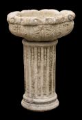 A reconstituted stone circular garden pedestal urn:, decorated with foliage,