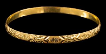 A gold coloured bangle: with incised decoration, stamped '22c', 7cm wide, 15gms.
