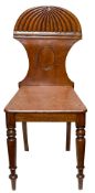 A late Regency carved mahogany hall chair:, with reeded and waisted domed back and solid seat,