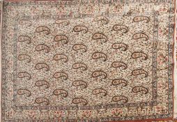 A Kirman rug:, the ivory field with an all over geometric boteh and leaf and floral design,