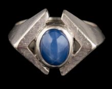 A star sapphire ring: the oval cabochon star sapphire collet set between textured shoulders,