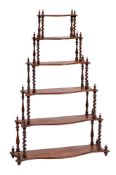 A Victorian walnut serpentine fronted six tier graduated whatnot:,