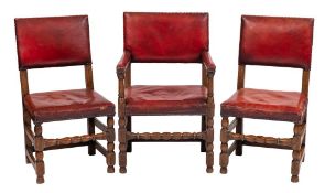 A set of six oak dining chairs in the Cromwellian taste:, with brass studded red leather backs,