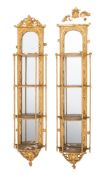 A pair of Victorian later gilt gesso four tier serpentine fronted hanging mirrored whatnots:,